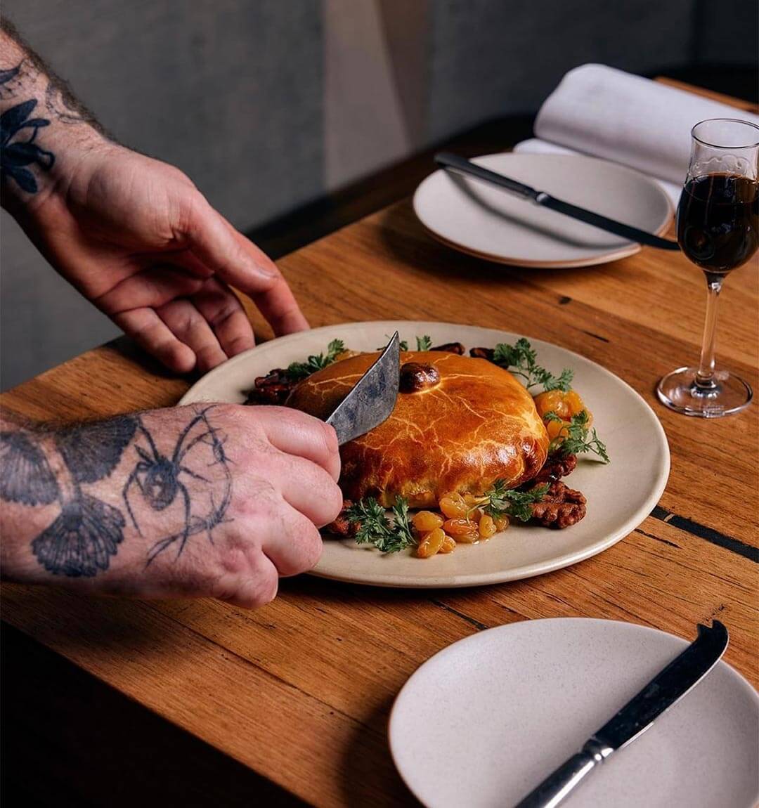 Delicious baked cheese dish at a fine dining restaurant in Healesville, presented by a chef with tattoos on his arms.